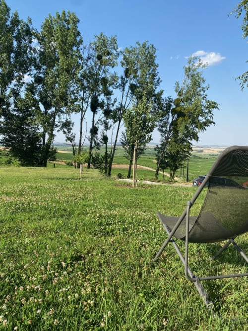 Chaise de camping dans une prairie verdoyante avec grands arbres et champs agricoles ondulants à La Cour Tellier, Rilly-la-Montagne