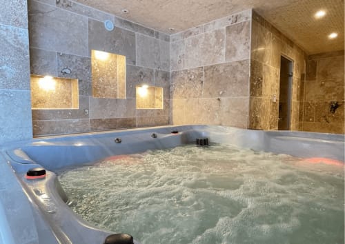 Baignoire spa luxueuse avec eau bouillonnante dans une salle de bien-être carrelée moderne au Domaine Les Racines, Croix-Moligneaux