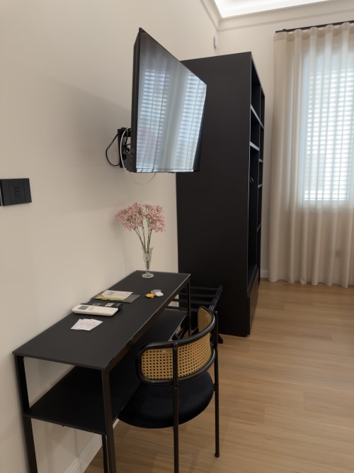 Moderna zona di lavoro presso Maison Riviera con scrivania nera, sedia e monitor in luminosa stanza a Reggio di Calabria