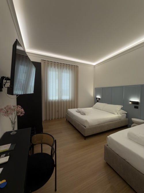 Camera moderna presso la Maison Riviera a Reggio di Calabria con letti gemelli, scrivania, TV a schermo piatto e illuminazione ambiente soffitto