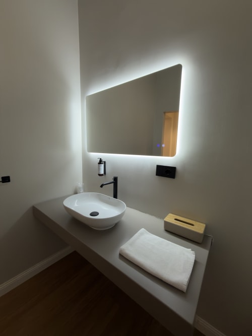 Bagno moderno a Maison Riviera con specchio illuminato, lavabo bianco e amenities a Reggio di Calabria
