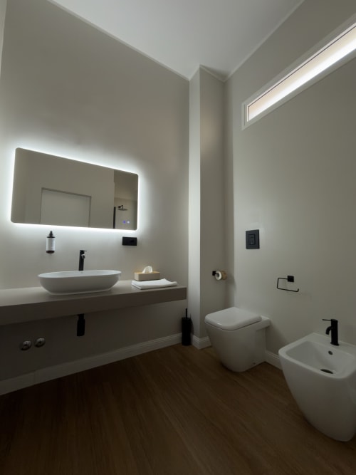 Bagno moderno nella suite Maison Riviera Deluxe, Reggio di Calabria, con specchio illuminato, lavabo d'appoggio, bidet e