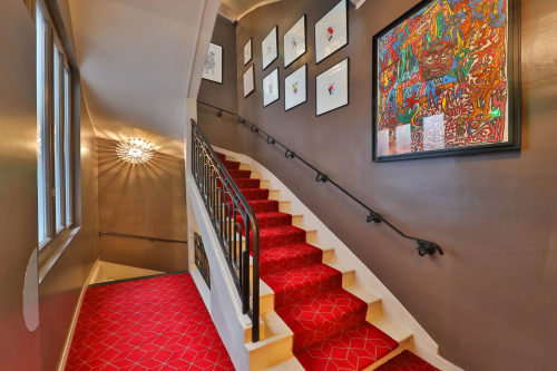 Elegant staircase at Hôtel Louvre Richelieu Paris with red runner, artwork, and brass railings