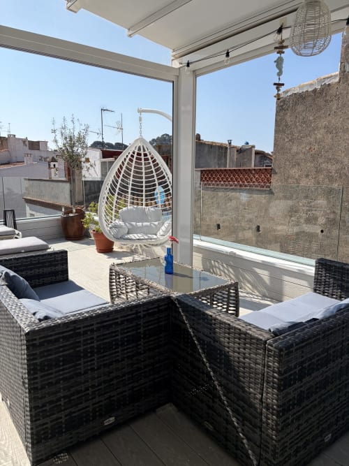 Terraza de lujo en la azotea del Hotel Boutique Mamma Mia Tossa con silla colgante tipo huevo blanca, mobiliario de mimbre y vistas de la ciudad