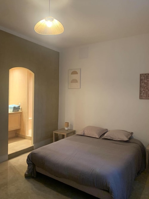 Chambre moderne de l'appartement Le Cocon Urbain à Carcassonne, avec luminaire suspendu et salle de bain attenante