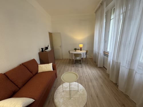 Salon moderne à Carcassonne avec canapé rouille, table ronde et vue sur la ville par grandes fenêtres