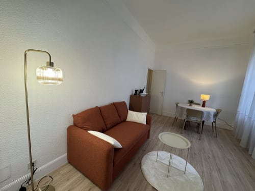 Salon moderne de l'appartement Mi Casa Es Su Casa à Carcassonne avec canapé rouille, lampadaire et décoration minimaliste