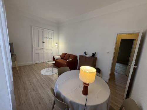 Salon moderne de l'appartement Mi Casa Es Su Casa à Carcassonne avec table à manger, canapé rouille et vue sur la ville