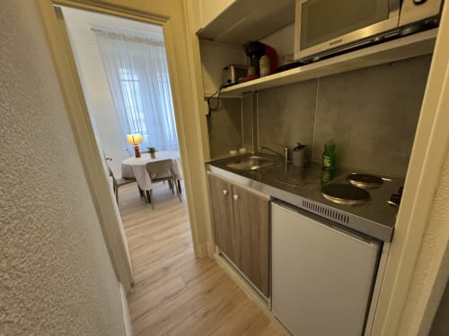 Petite kitchenette de l'appartement Le Cocon Urbain à Mi Casa Es Su Casa, Carcassonne avec cuisinière, évier et vue sur l'espace repas