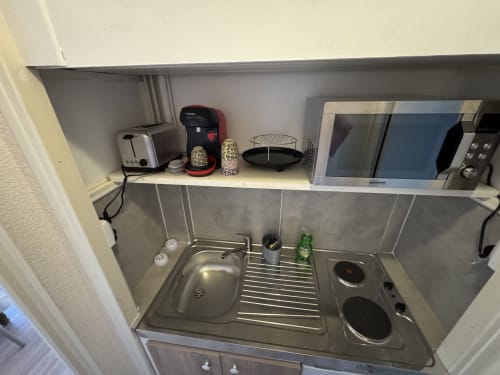Petite kitchenette dans l'appartement Le Cocon Urbain à Carcassonne, équipée d'un évier, plaque de cuisson, micro-ondes et électroménagers