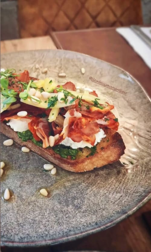 Gourmet open-faced sandwich with crispy bacon, white cheese, and fresh microgreens on toasted bread at Clos De La