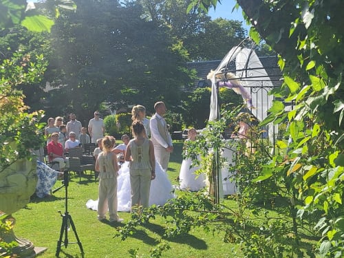 Cérémonie de mariage dans le jardin de La Cour d'Hortense B&B à Sailly-Flibeaucourt, invités sous une arche couverte de lierre