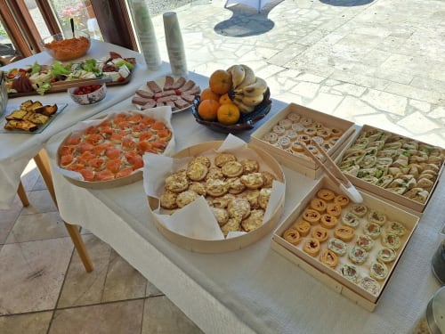 Buffet en plein air à La Cour d'Hortense avec charcuterie, saumon fumé, pâtisseries, fruits et salades fraîches sous le soleil