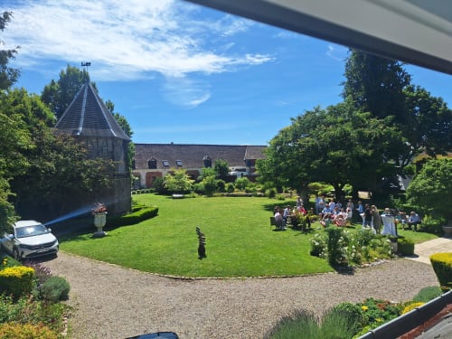 Les jardins de la Cour d'Hortense à Sailly-Flibeaucourt avec pelouse soignée, tour historique et invités réunis en plein air