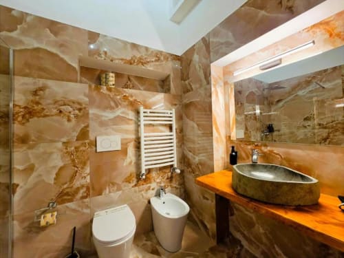Lussuoso bagno dell'hotel Vatican Nice Holiday Rome con pareti in marmo, lavabo moderno, scaldasalviette e doccia walk-in
