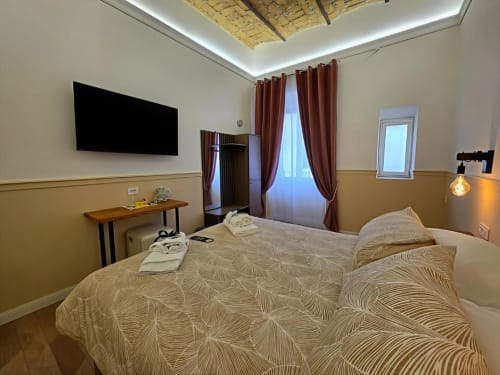 Lussuosa camera tripla al Vatican Nice Holiday di Roma con letto queen, TV a schermo piatto, tende bordeaux e cortile interno