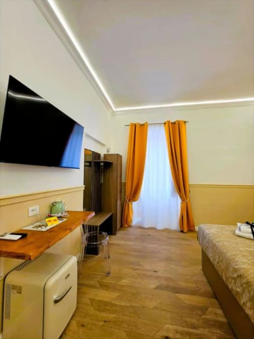 Camera Tripla Superiore al Vatican Nice Holiday Luxury Rooms di Roma con TV a schermo piatto, pavimenti in legno e tende arancioni