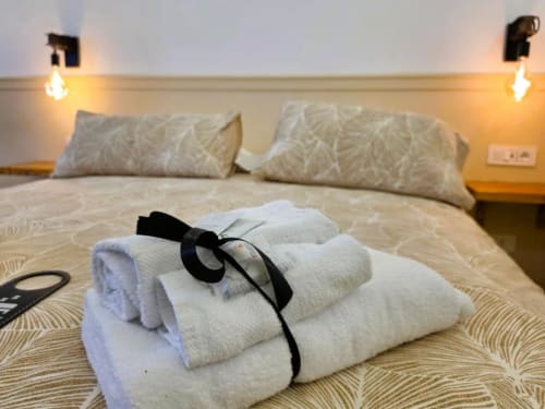 Asciugamani bianchi arrotolati con nastro nero sul letto di Vatican Nice Holiday Luxury Rooms a Roma