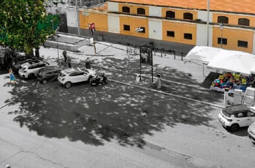 Parcheggio esterno della struttura Vatican Nice Holiday Luxury Rooms a Roma con automobili e facciata gialla