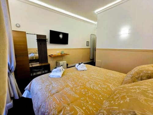 Deluxe Triple Room al Vatican Nice Holiday Luxury di Roma con biancheria dorata, TV a schermo piatto e arredamento classico
