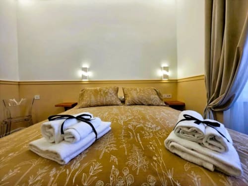 Camera Tripla Deluxe presso Vatican Nice Holiday Luxury Rooms Roma, con biancheria dorata, asciugamani e vista sulla città