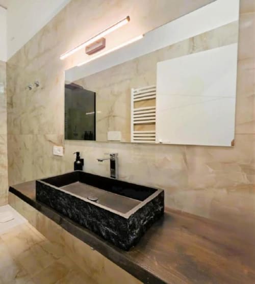 Bagno moderno con lavabo rettangolare nero, piastrelle in marmo, ampio specchio e illuminazione LED presso Vatican Nice Holiday Luxury