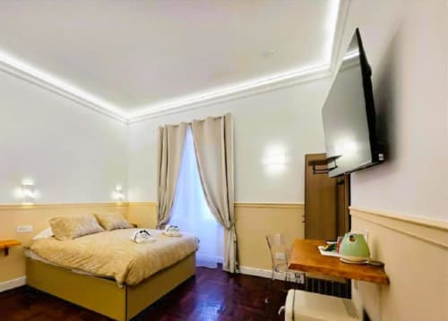 Camera lussuosa di Vatican Nice Holiday a Roma con letto giallo, TV schermo piatto, scrivania e elegante illuminazione del soffitto