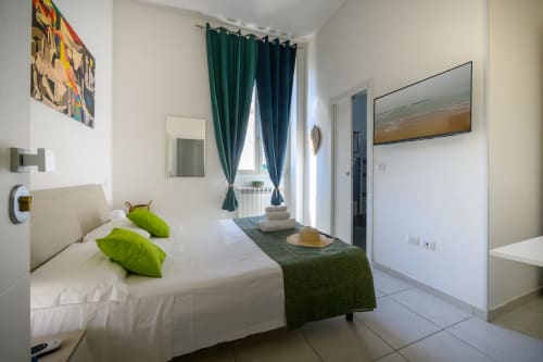 Modern bedroom at Dimore Salentine in Lecce with white bed, green accents, city view, and contemporary furnishings