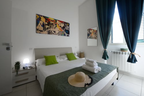 Modern bedroom at Dimore Salentine in Lecce with queen bed, green accents, city view window, and abstract artwork