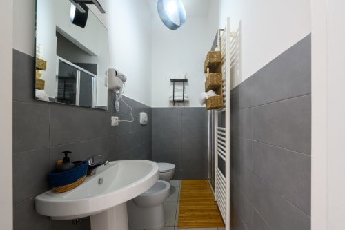 Modern bathroom in Dimore Salentine, Lecce with gray tiled walls, pedestal sink, toilet, and wooden flooring