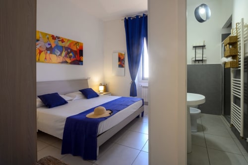 Bright bedroom at Dimore Salentine in Lecce with blue accents, en-suite bathroom visible, city view window