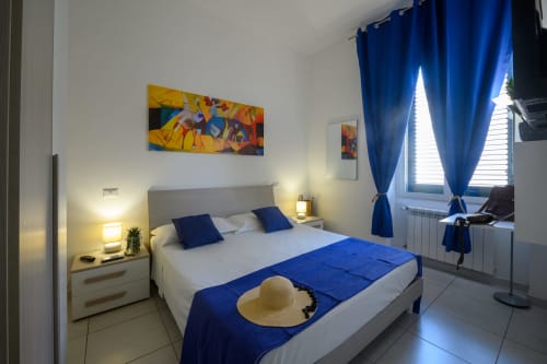 Bright bedroom at Dimore Salentine in Lecce with blue accents, queen bed, modern amenities, and city view window
