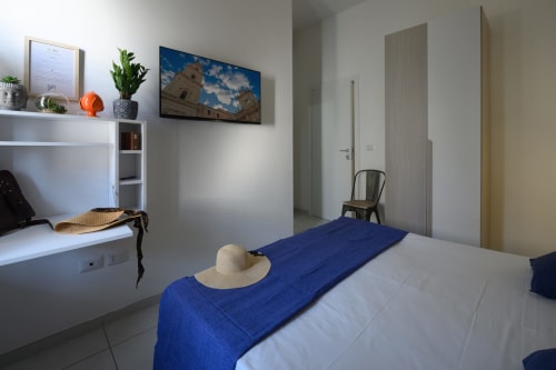 Modern bedroom in Lecce with blue accents, desk, TV, and city views at Dimore Salentine