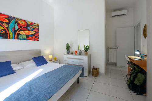 Bright bedroom at Dimore Salentine in Lecce with queen bed, blue accents, colorful wall art, and modern furnishings