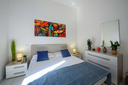 Modern bedroom at Dimore Salentine Lecce with colorful art, blue pillows, white bedding, and contemporary furnishings