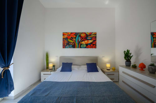 Modern bedroom at Dimore Salentine in Lecce with blue accents, colorful artwork, and city views