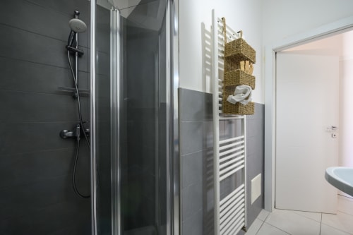 Modern bathroom at Dimore Salentine in Lecce with shower enclosure, heated towel rack, and woven storage baskets