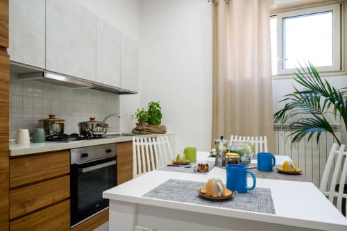 Modern kitchen and dining area at Dimore Salentine in Lecce, featuring white cabinetry and wooden accents with city views