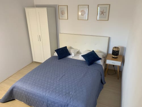 Quarto moderno no albergue Anchor House Albufeira com cama acolchoada azul, travesseiros azul-marinho, cabeceira creme e decoração litorânea