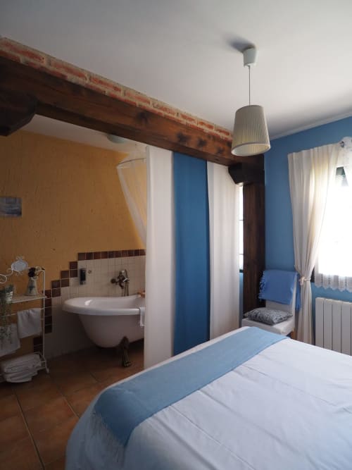 Dormitorio moderno con baño en suite en Rural Senda del Duratón Apartments, con paredes azules, vigas de madera y detalles blancos