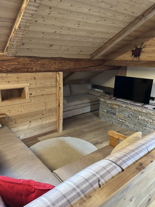 Suite loft accogliente con travi in legno, zona living, TV e parete in pietra a Residenza Verdebjo, Gressoney-Saint-Jean