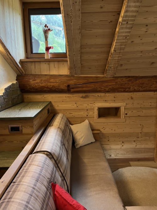 Accogliente suite loft in legno presso Residenza Verdebjo con vista montagna, letto, accesso sauna e finestra alpina panoramica