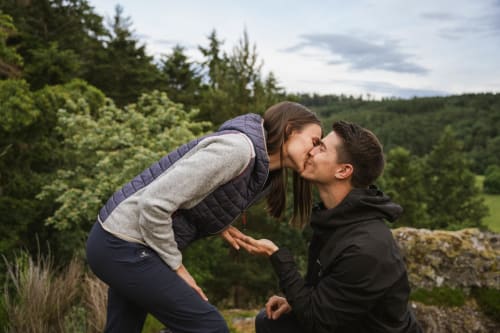 Couple s'embrassant en plein air avec vue sur la forêt aux Cabanes du Nideck, Oberhaslach