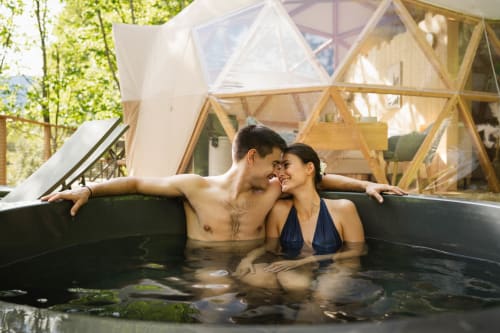 Couple se relaxant dans le bain à remous extérieur des Cabanes du Nideck, Oberhaslach avec dôme géodésique