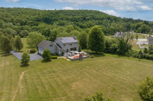 Modern home with pool deck at Malkita Homes in Highland Mills surrounded by green lawn and forested hills
