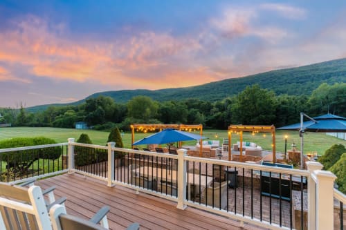 Malkita Homes Highland Mills deck with sunset views, blue umbrellas, and mountain landscape at dusk