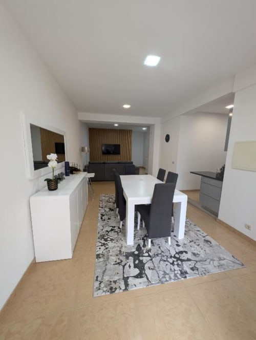 Sala de jantar e cozinha moderna no Villas Eden com mesa branca, cadeiras pretas e vista para a sala de estar em Fão, Portugal