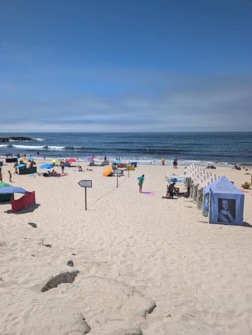 Praia arenosa movimentada em Fão, Portugal com guarda-sóis coloridos, tendas e banhistas aproveitando as ondas do mar