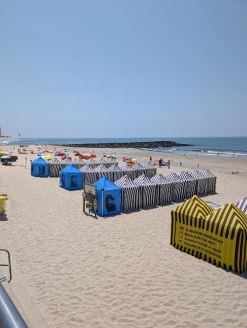 Praia de Fão com cabanas de praia coloridas e listradas, vestiários azuis e vista para o oceano em Portugal