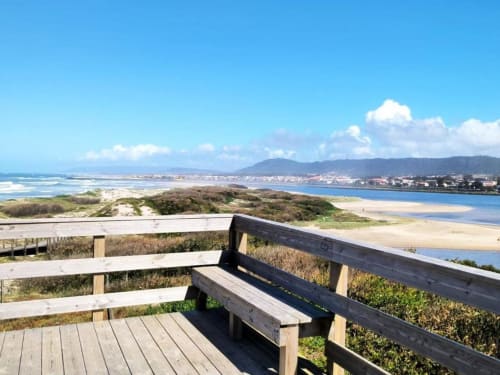 Deck de madeira com banco com vista para a paisagem costeira, praia e dunas na propriedade rural Villas Eden em Fão, Portugal